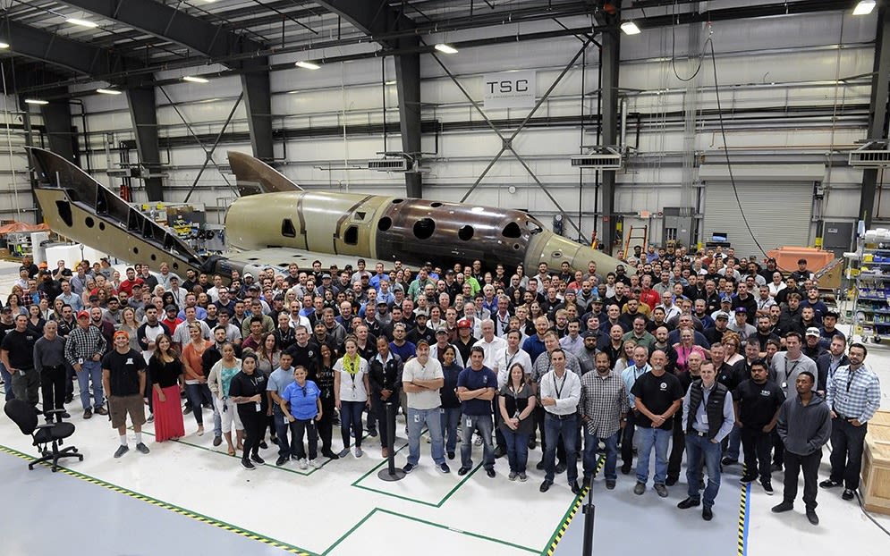 The Virgin Galactic team in the factory, standing together looking at the camera
