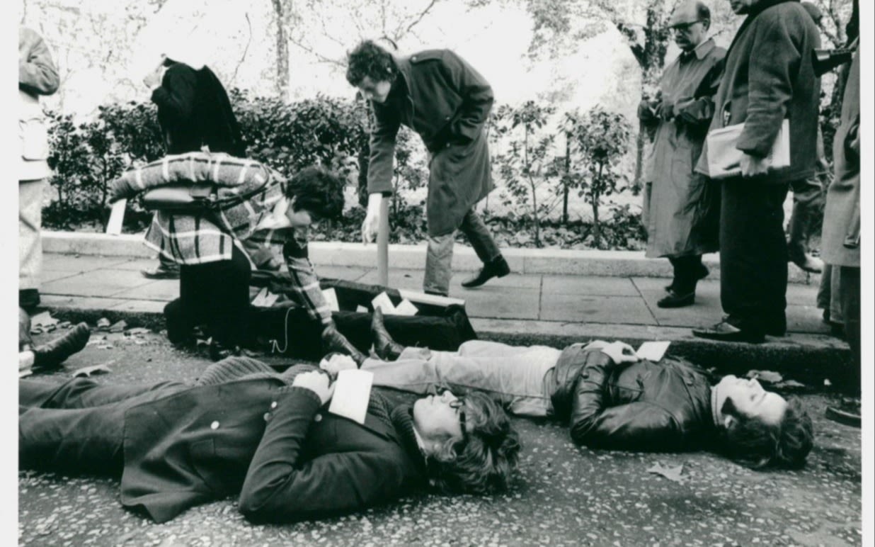 Black and white photo of a young Richard Branson and others lying down on the ground in protest 
