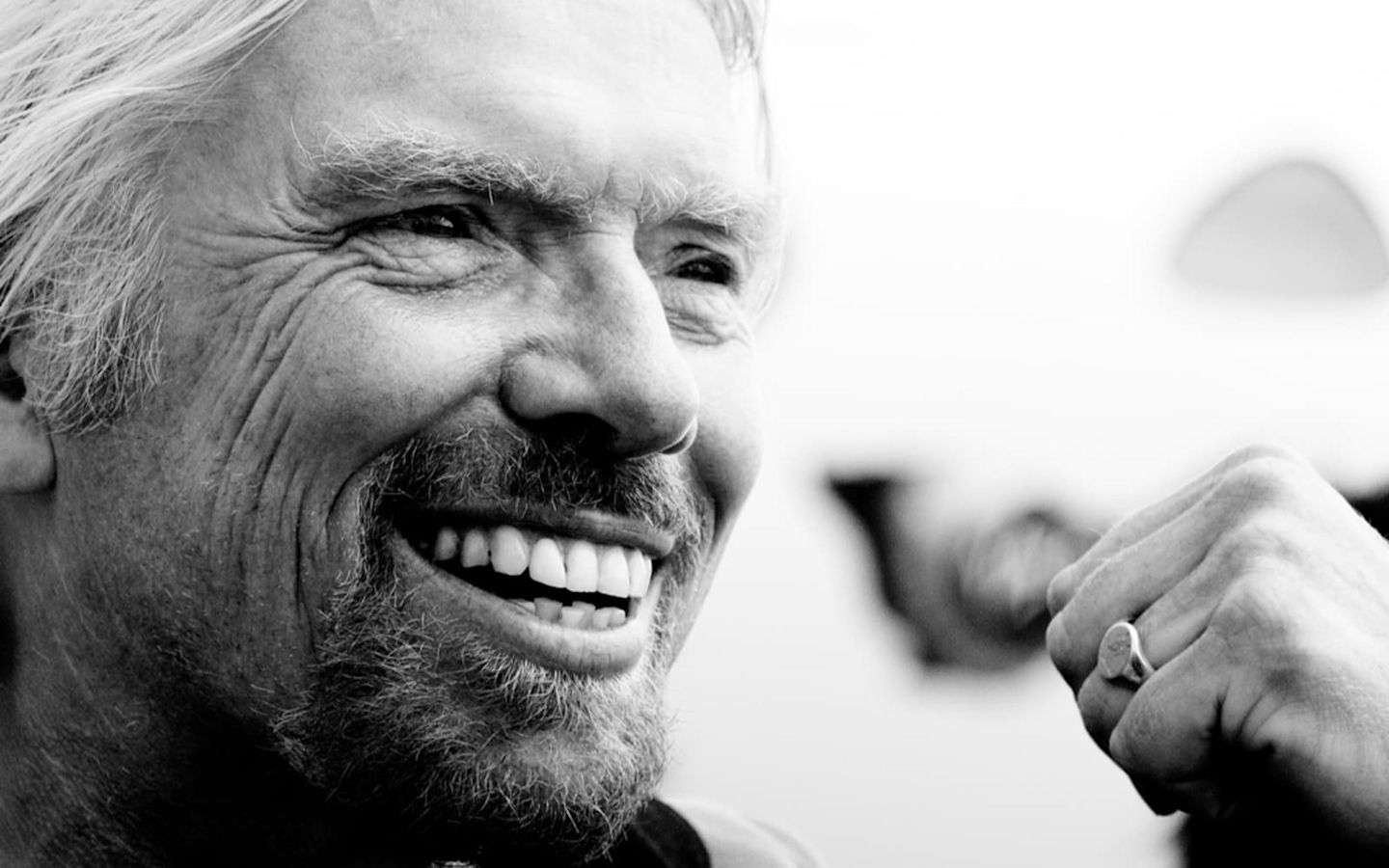Close up black and white photo of Richard Branson smiling with clenched fist