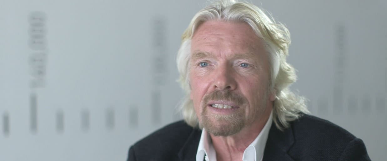 A head and shoulder shot of Richard Branson.  His face is neutral, mid-conversation