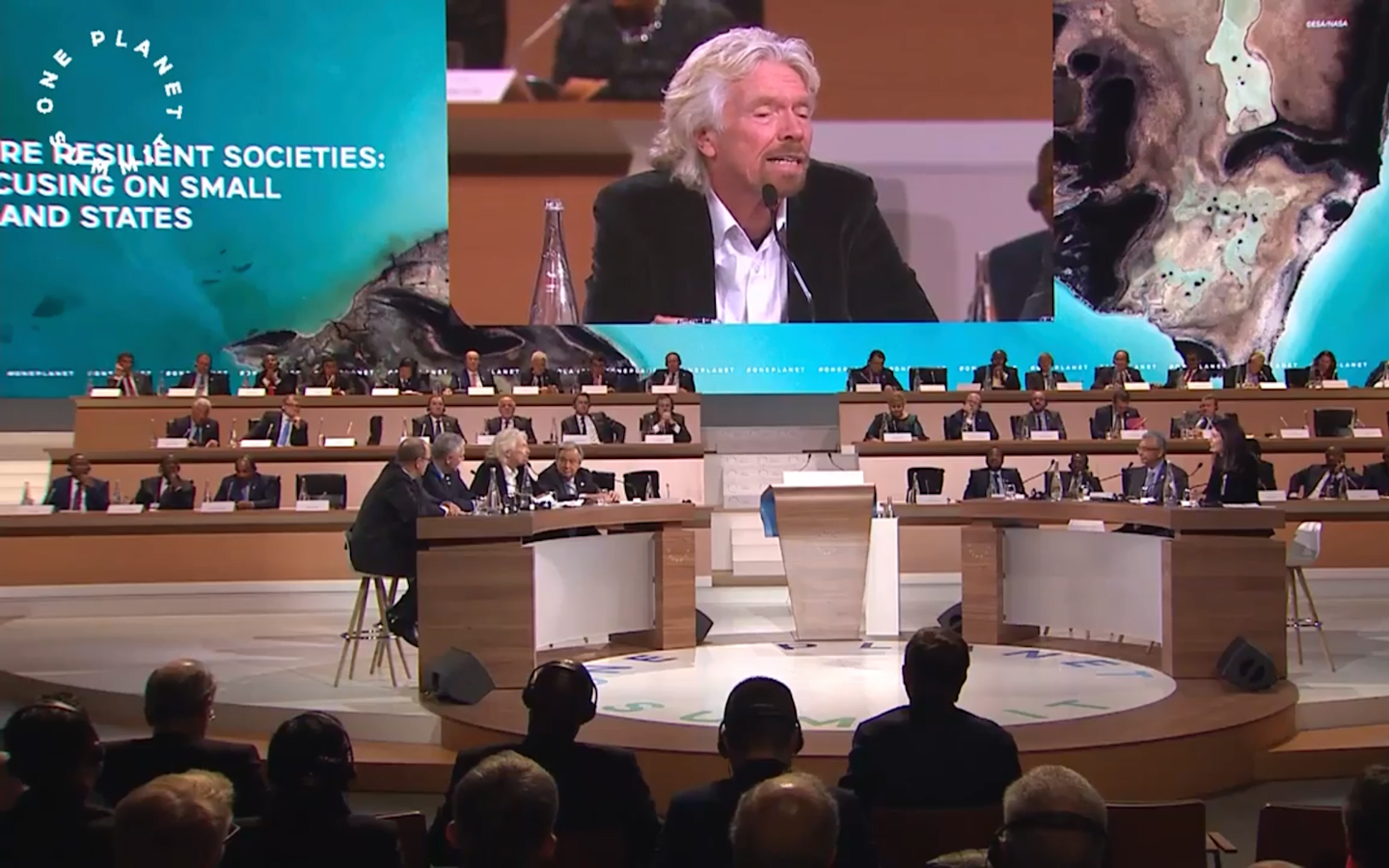 Several images of the One Planet Summit. One is of Richard Branson speaking, one is of the attendees sitting at tables, one is a meteorological image