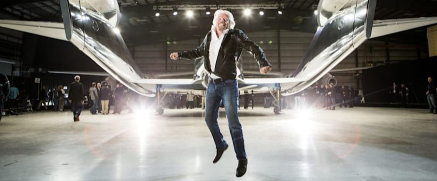 Richard Branson jumps in celebration in front of Virgin Galactic's VSS Unity