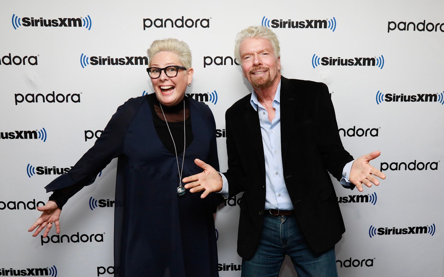 Richard Branson poses with arms outstretched beside Halla Tomas