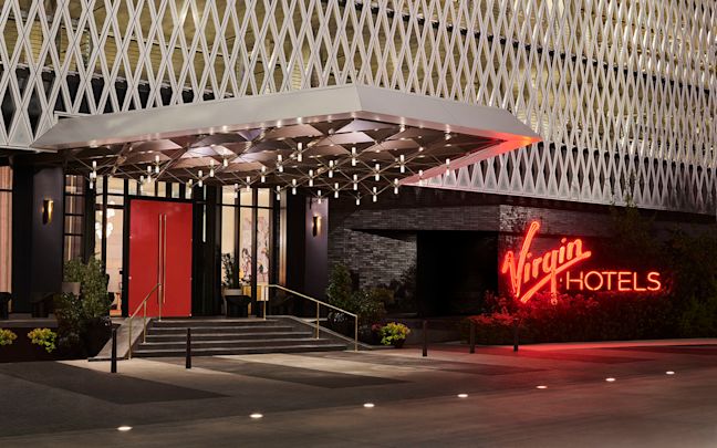 The entrance to Virgin Hotels Dallas, a red neon sign reads Virgin Hotels The entrance to Virgin Hotels Dallas, a red neon sign reads Virgin Hotels