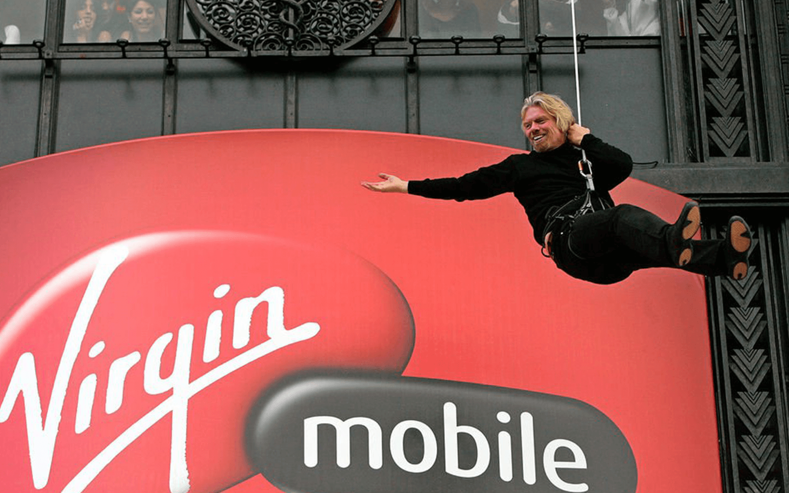 Richard Branson abseiling down a building with a giant Virgin Mobile logo on it