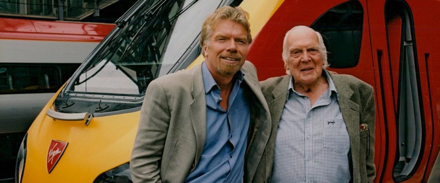Richard Branson and his father Ted Branson smiling in front of a Virgin Trains train
