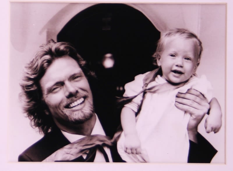 Black and white picture of Richard Branson holding up Sam Branson as a baby and smiling