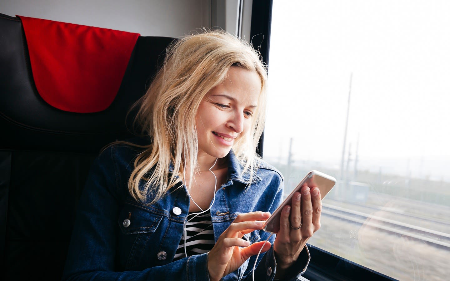Image of lady smiling on her phone on the train.