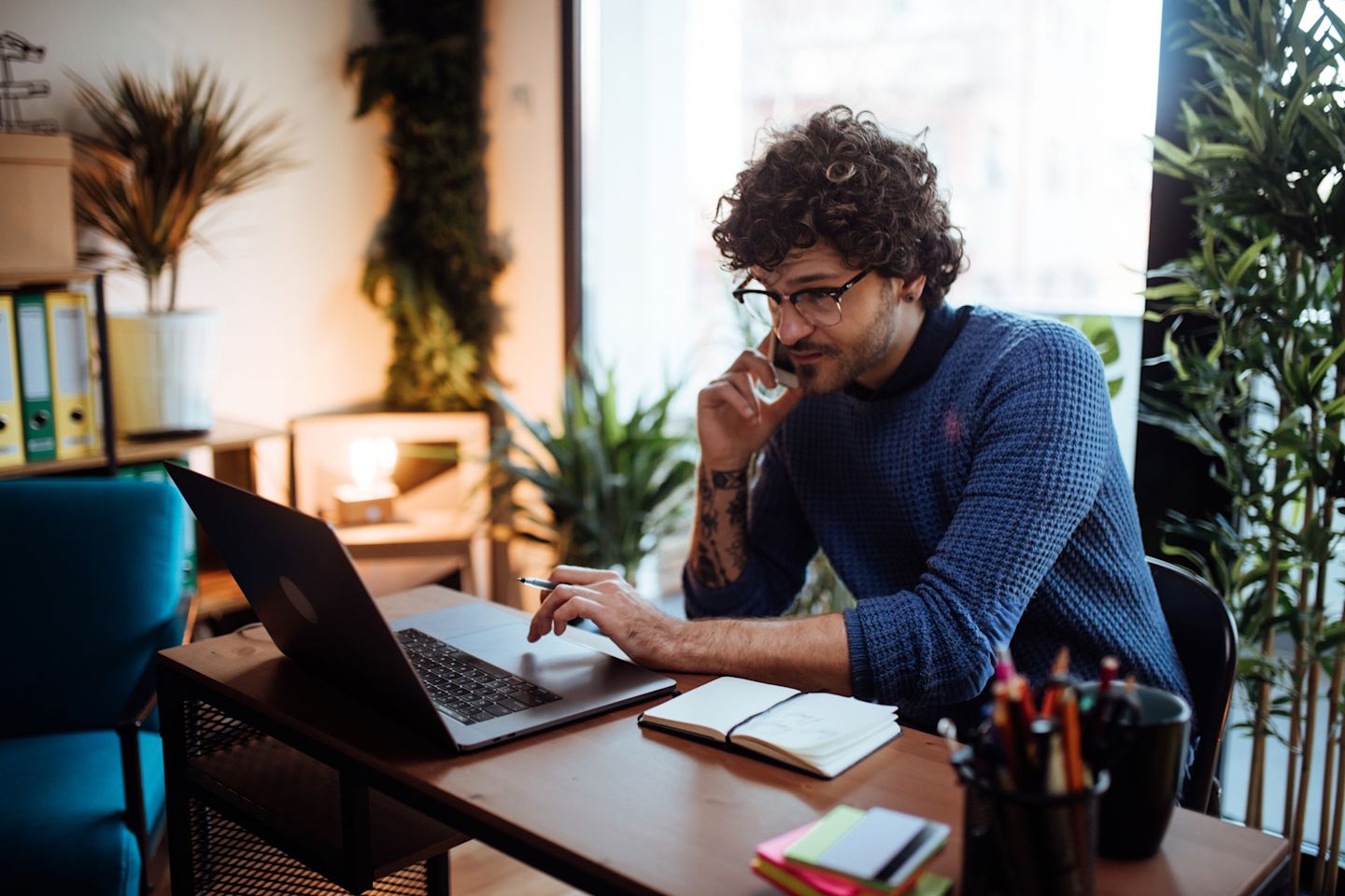 A man working from home, on the phone and using a laptop