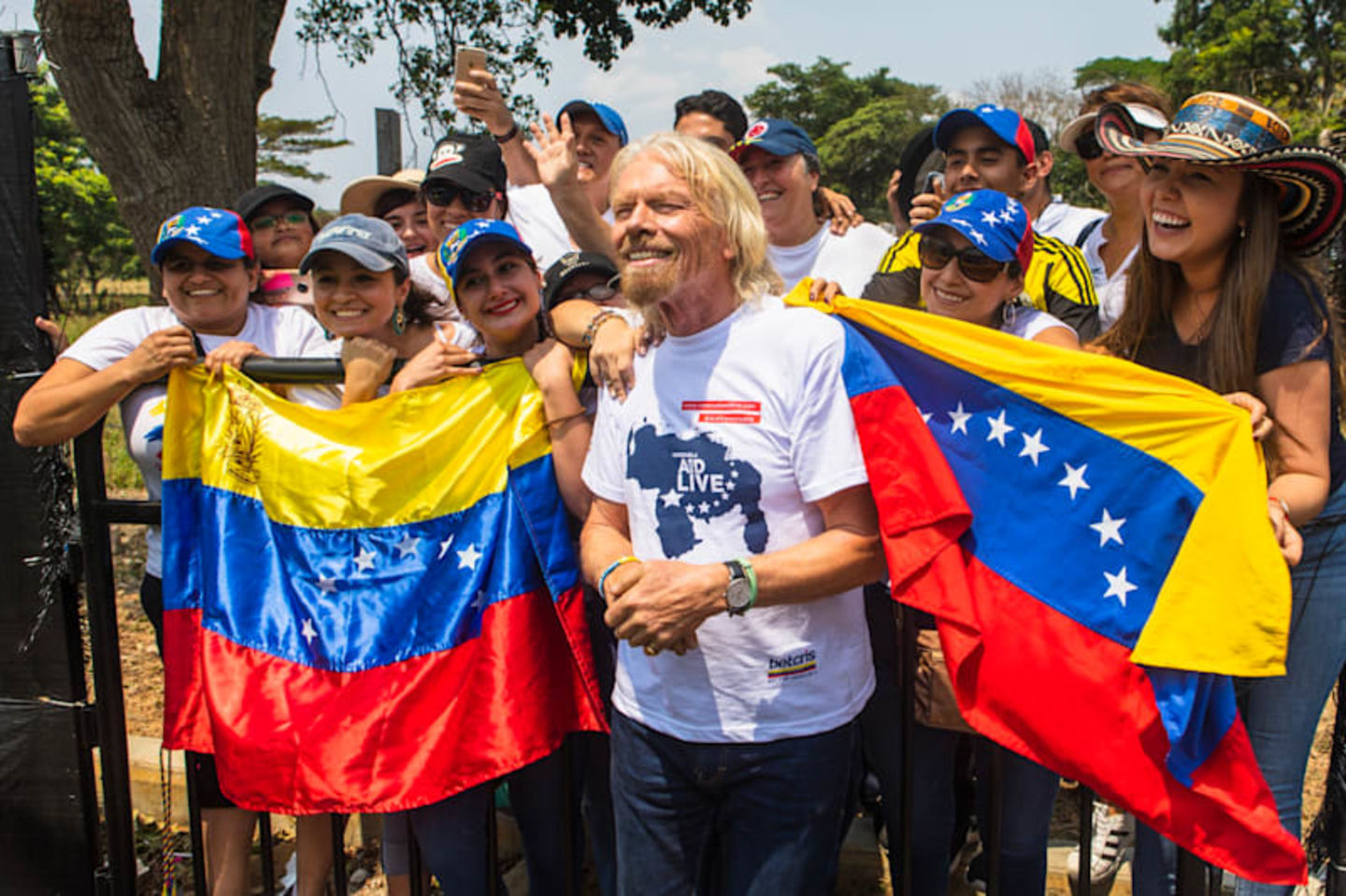Richard Branson in front of a crowd of people holding the flag of Venezuela