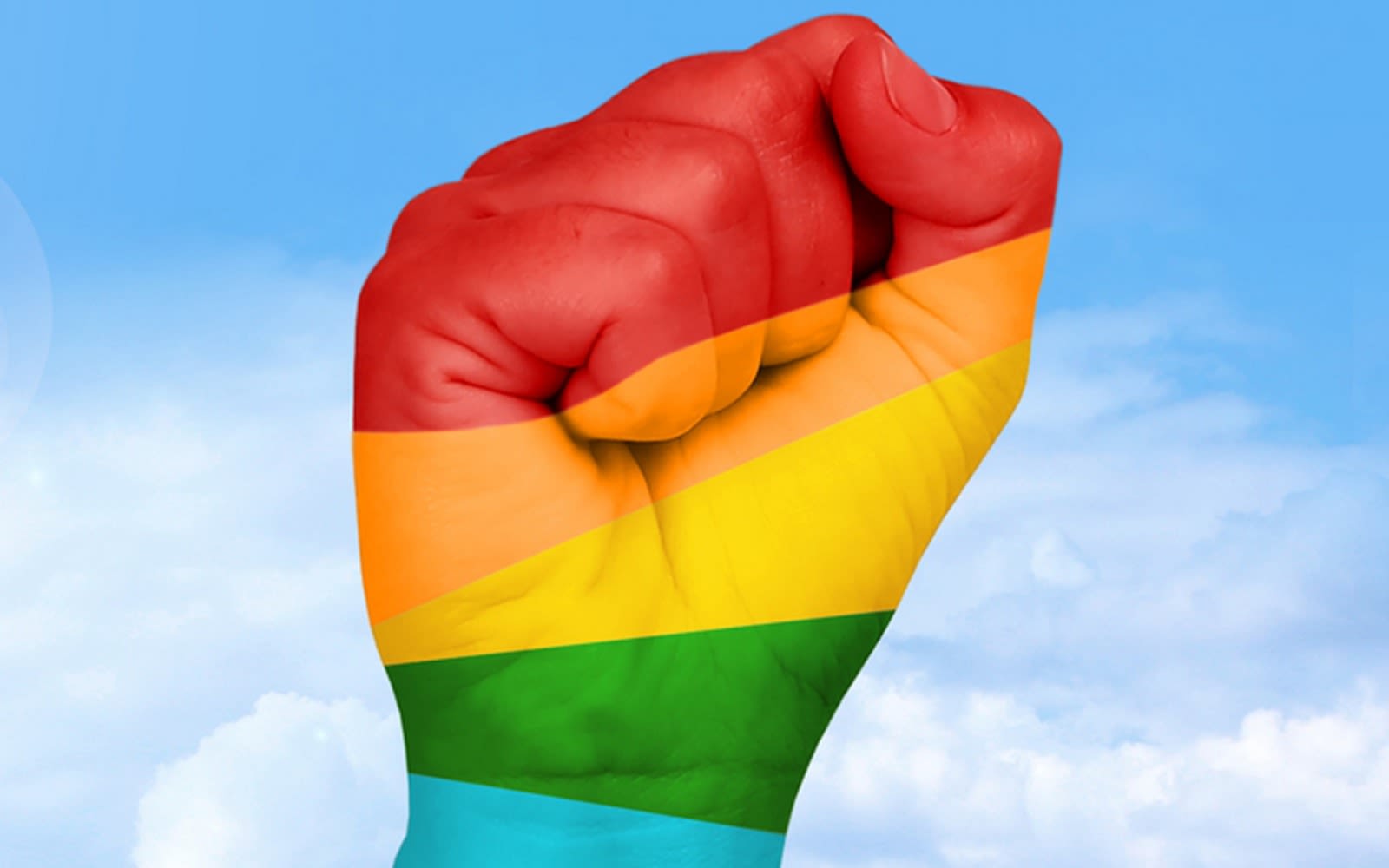 A clenched fist raised up with five colours of the rainbow in stripes across it - red, orange, yellow, green, blue