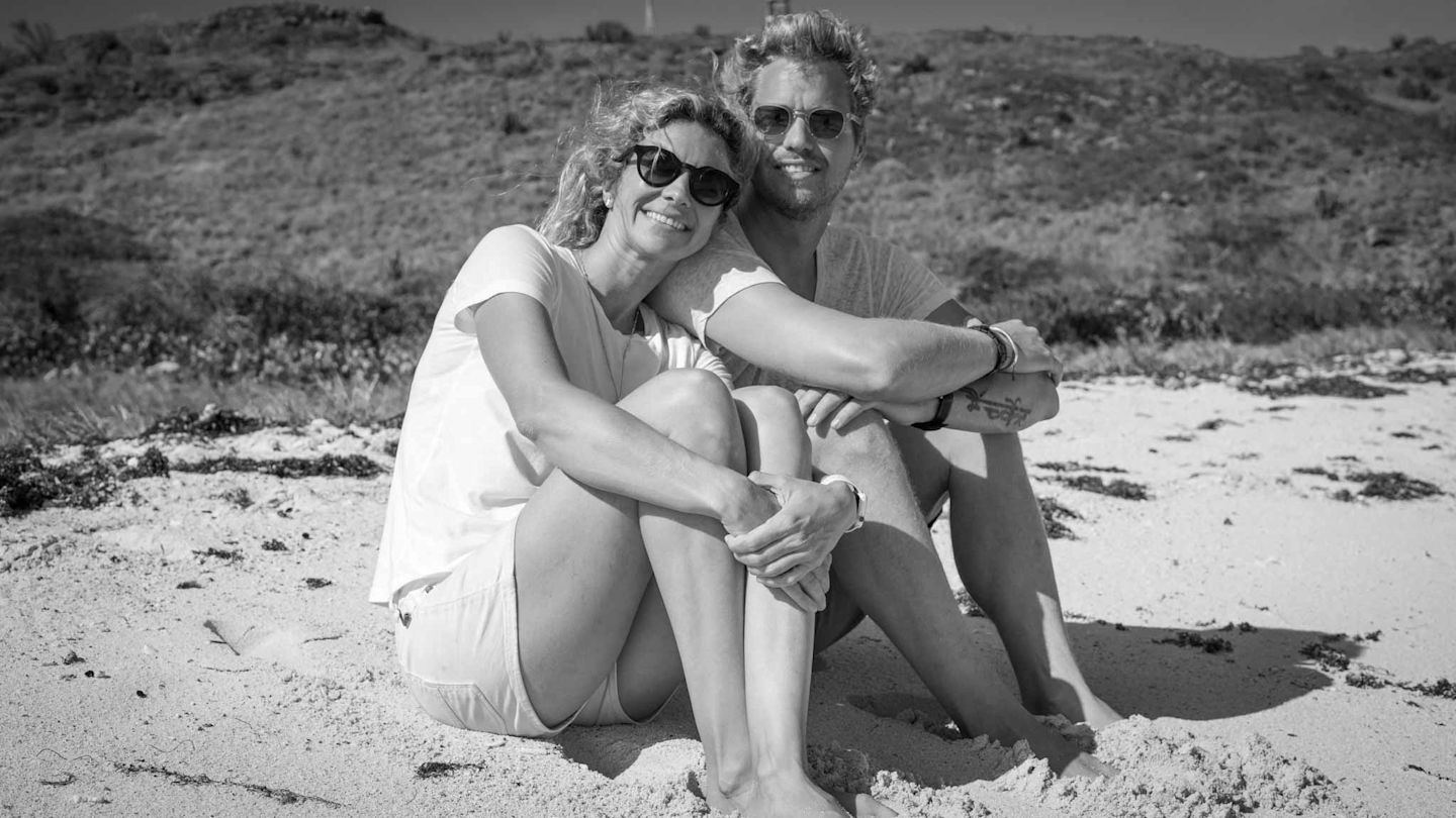 Holly Branson smiles with Sam Branson while sitting on a beach on Necker Island