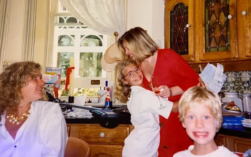 A young Holly Branson hugging a friend of Joan (left) and Sam Branson grinning to the camera
