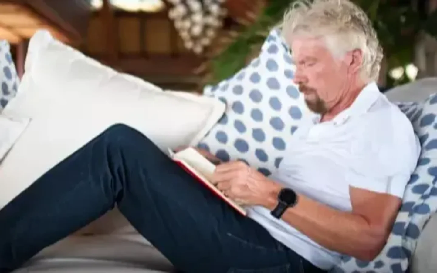 Richard Branson reading on a sofa