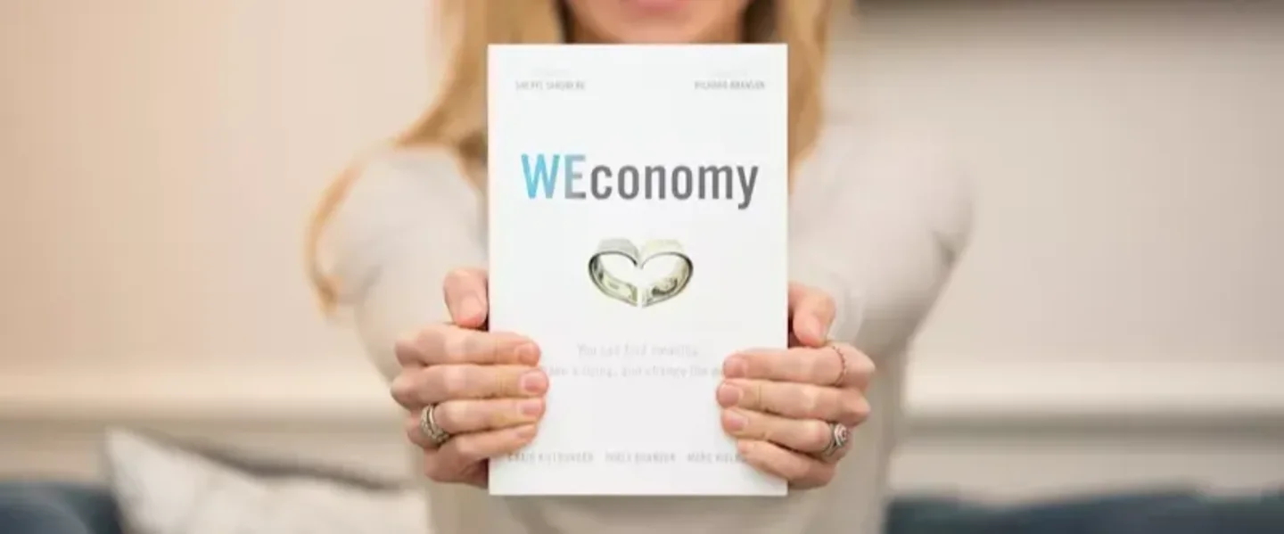 Holly Branson holding copy of WEConomy to the camera