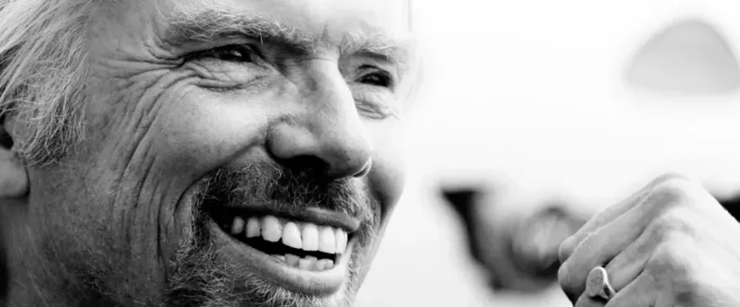 Black and white close up of Richard Branson smiling with a clenched fist 