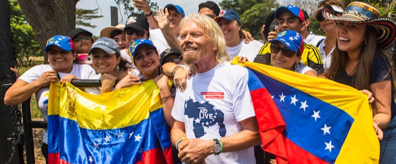 Richard Branson standing with a group of people holding Venezuelan flags