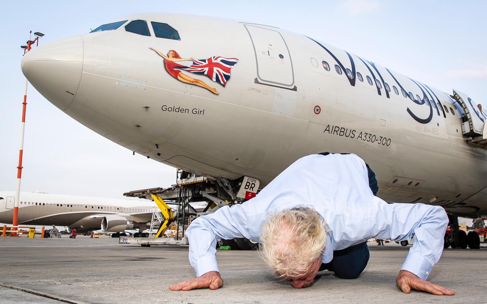 Richard Branson kisses the ground in front of a plane