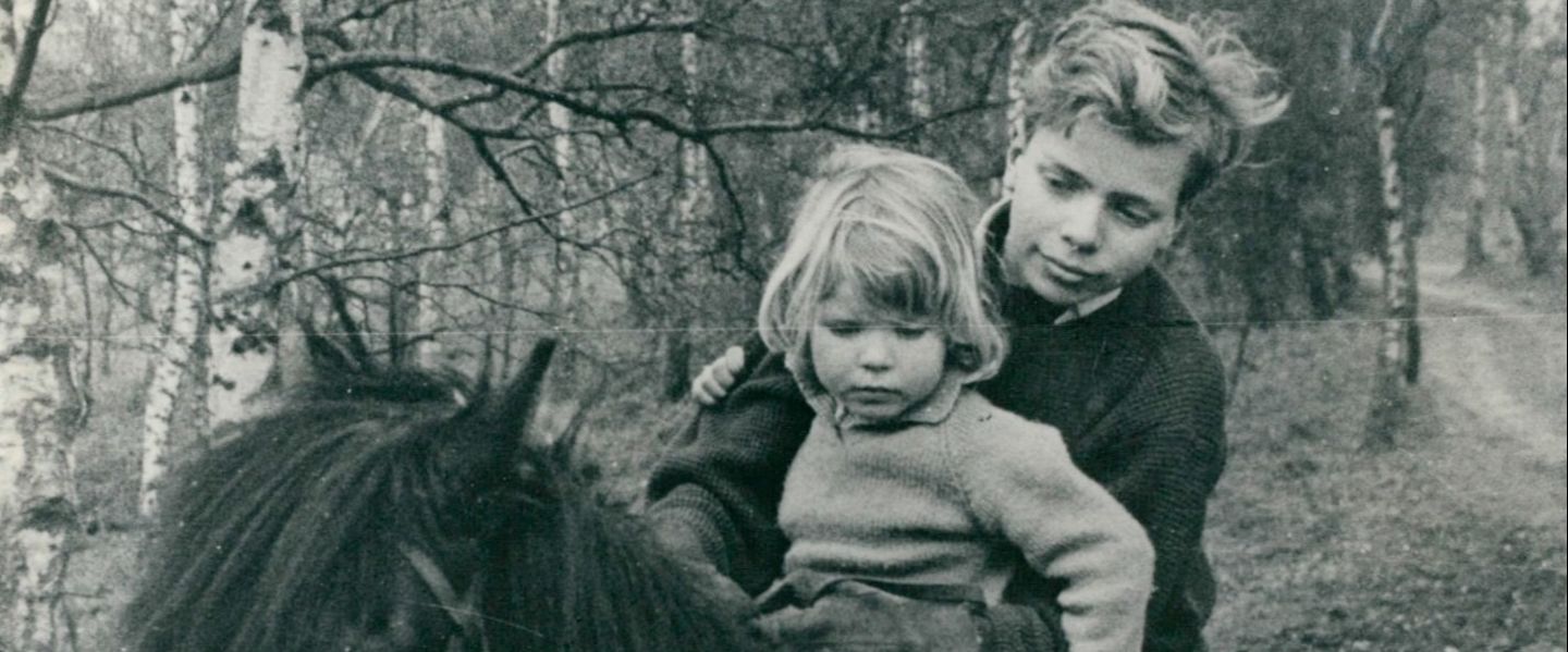 Black and white photo of Richard Branson as a boy and a small child riding a horse in a forest