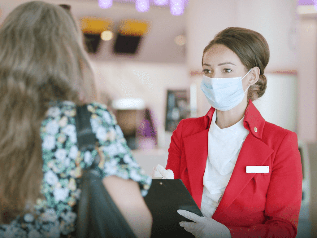 A female member of staff for Virgin Atlantic wearing a face mask speaking to a customer 
