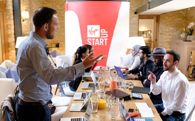 A group of Virgin StartUp founders in a meeting around a long table