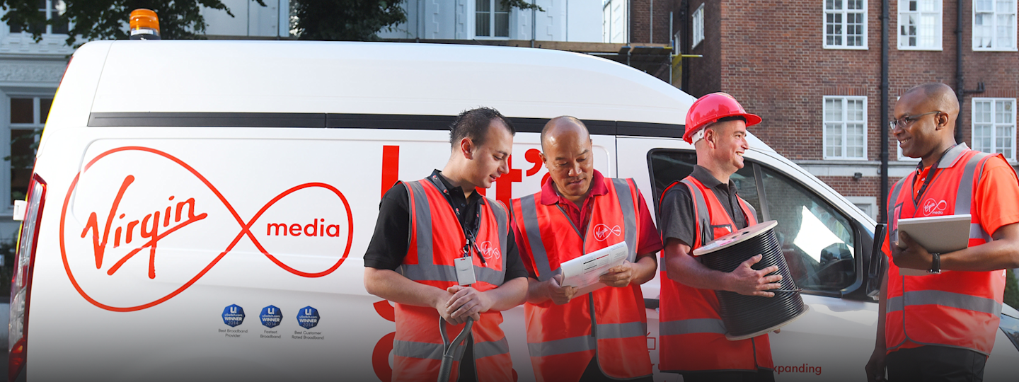 Four Virgin Media engineers stand next to a Virgin Media van