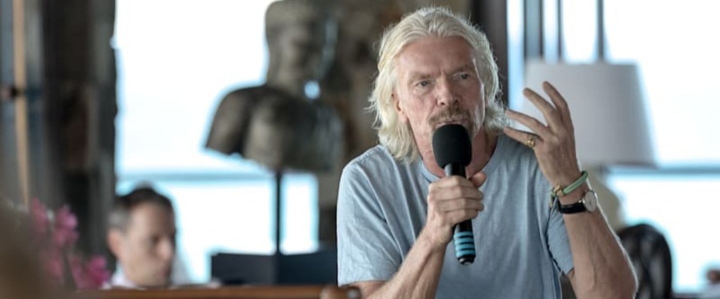 Richard Branson speaking into a hand-held microphone