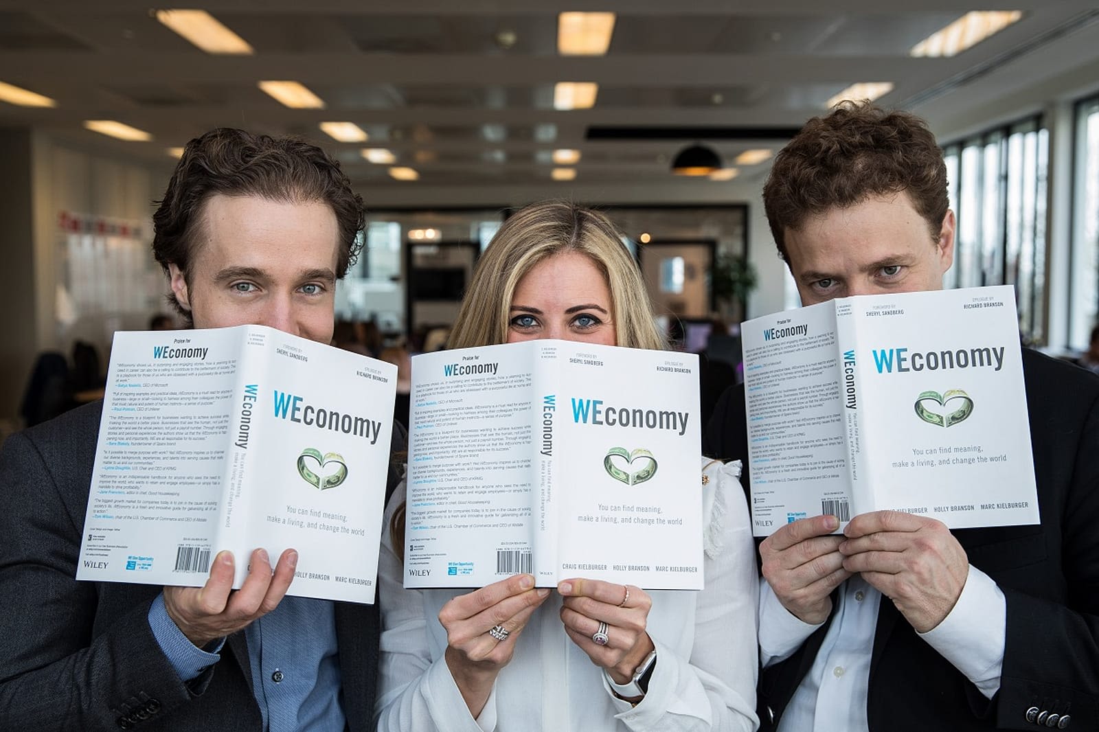 Holly Branson, Marc Kielburger and Craig Kielburger hold copies of their book WEconomy