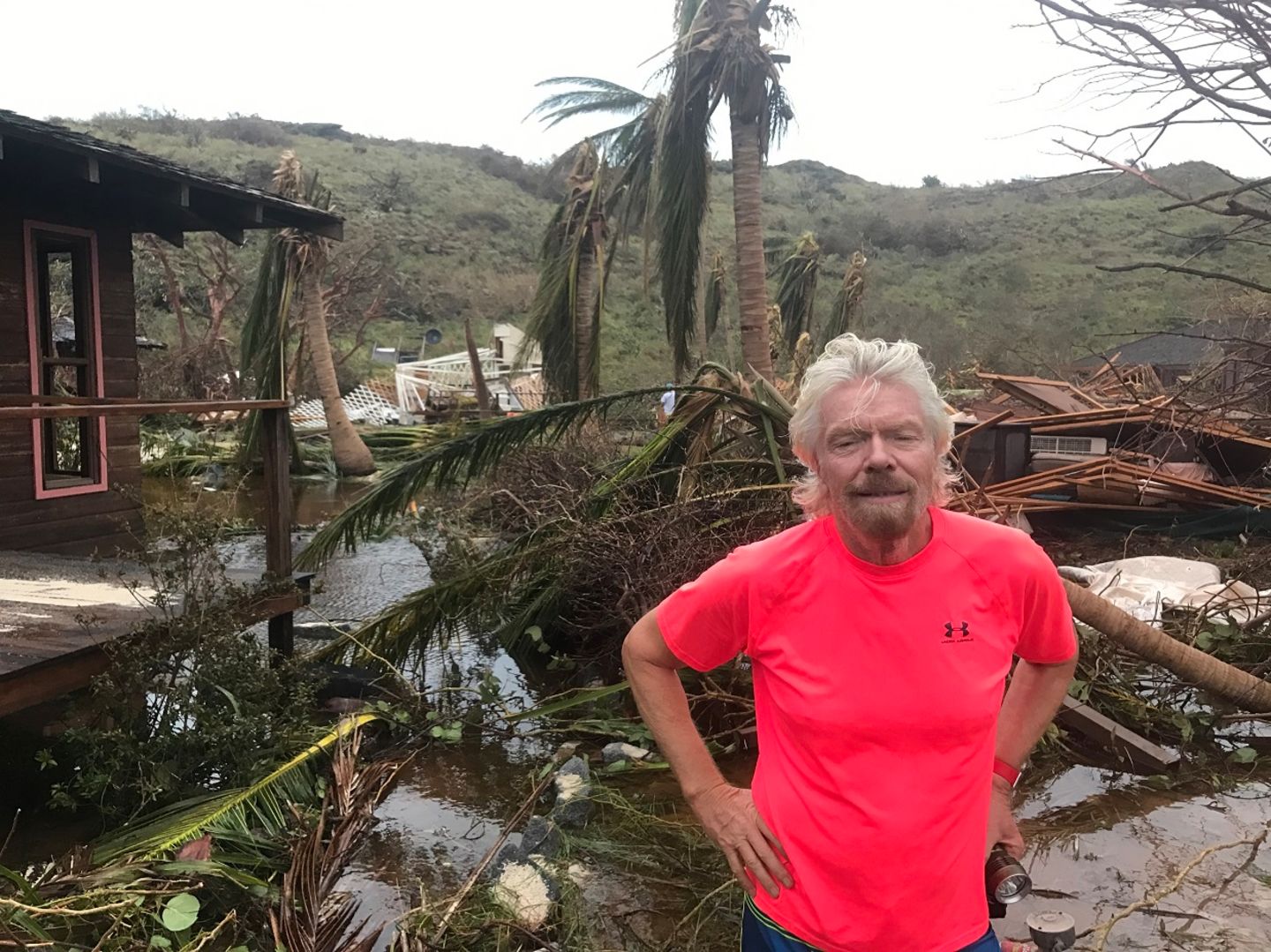 Richard Branson standing in front of the damage caused by hurricane irma on Necker Island
