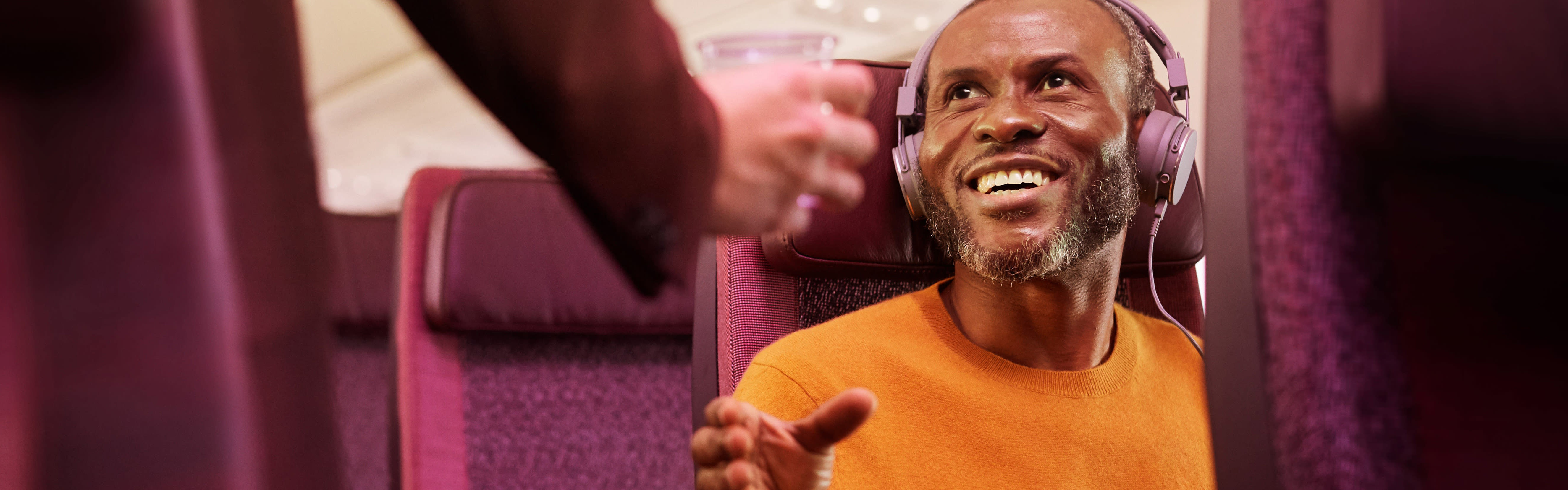 A man receiving a drink on a Virgin Atlantic flight