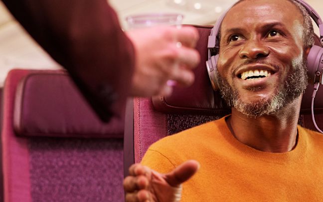 A man receiving a drink on a Virgin Atlantic flight A man receiving a drink on a Virgin Atlantic flight