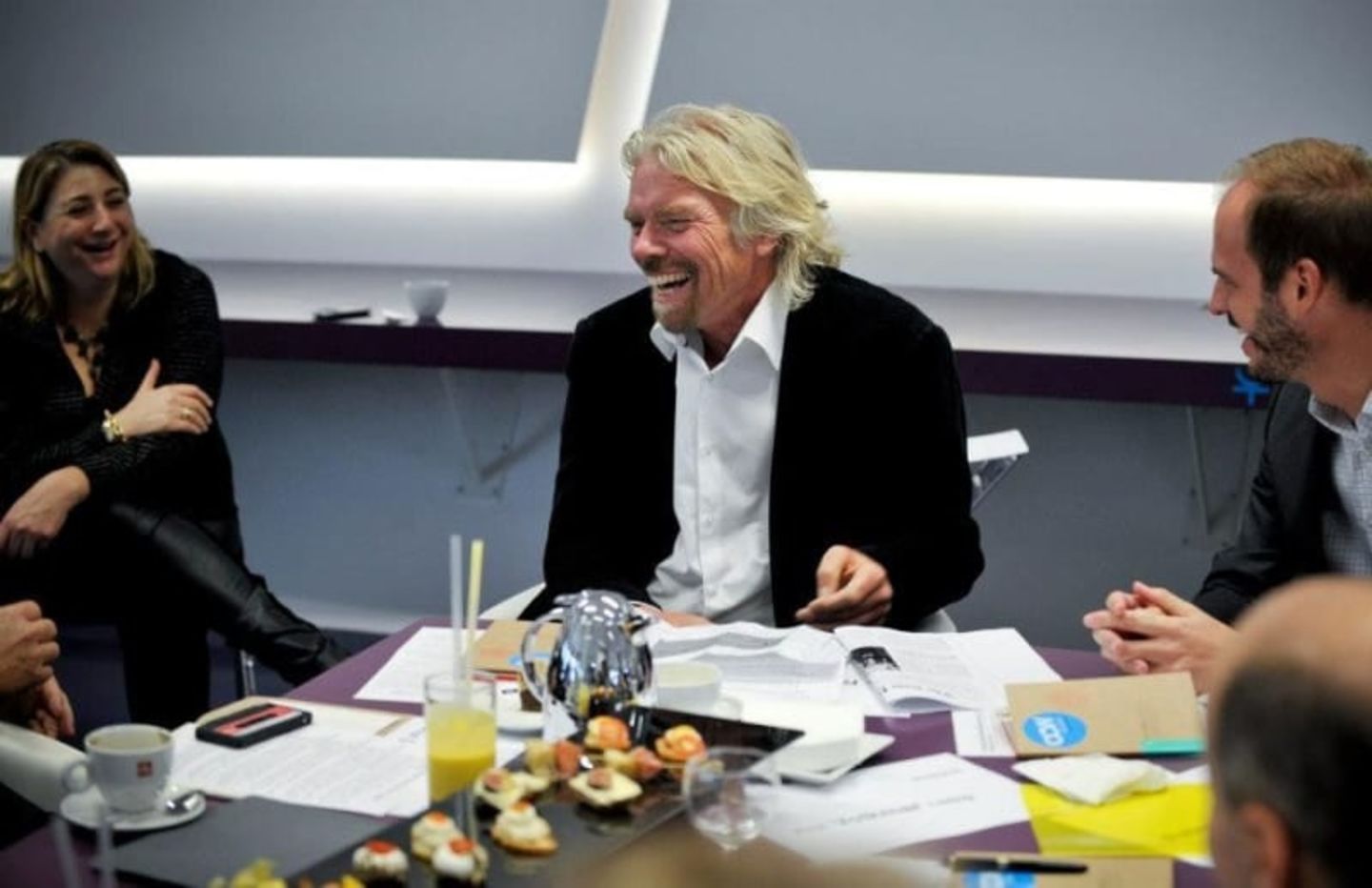 Richard Branson, sat in a meeting, laughing