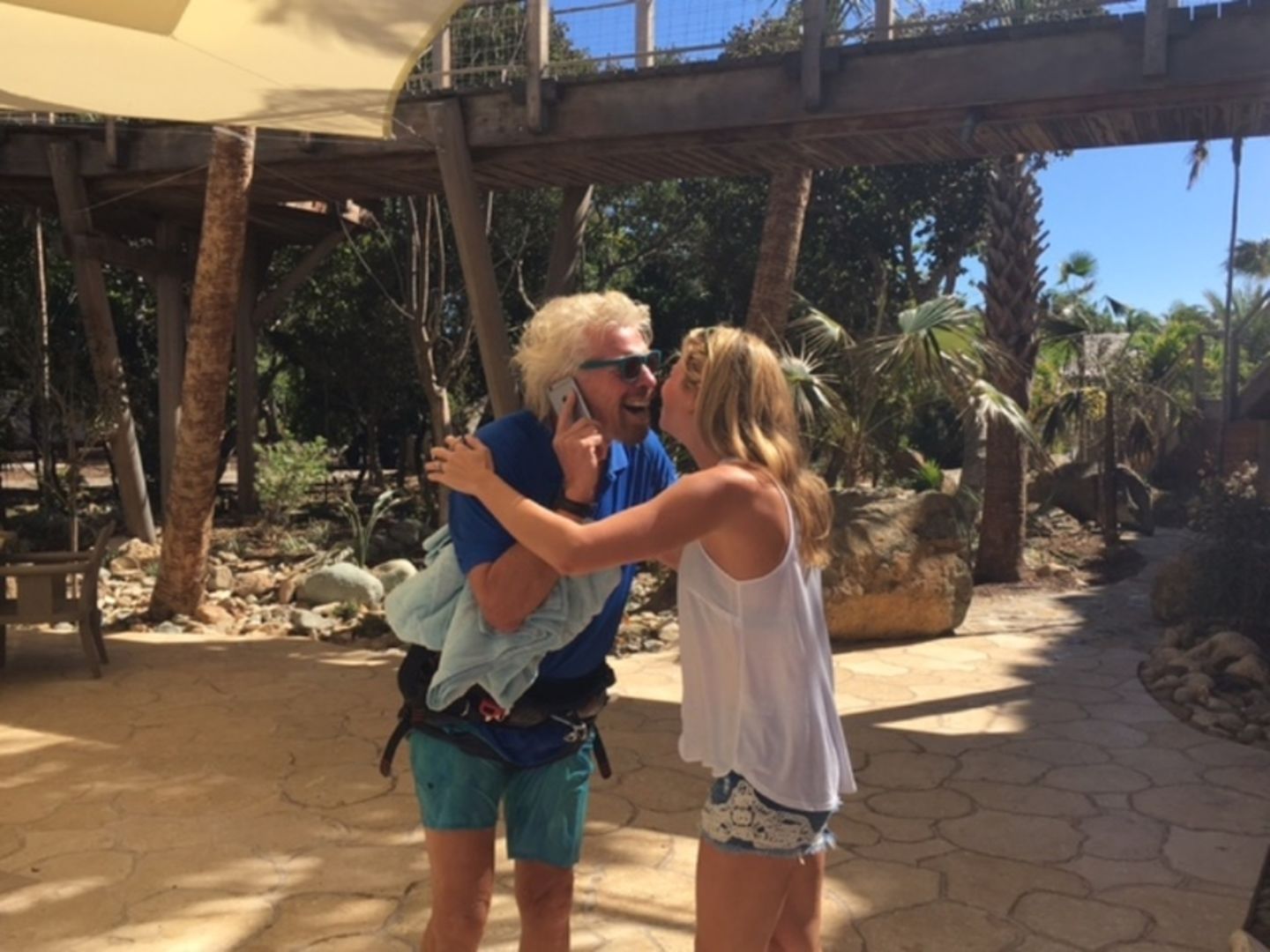 Richard Branson and Holly Branson hug, while Richard is on the phone