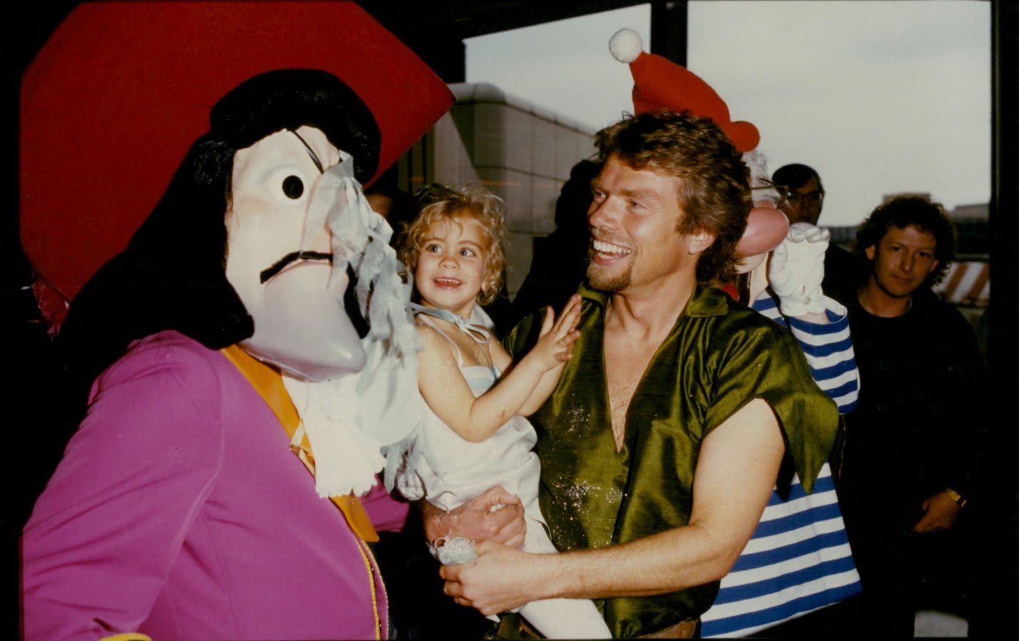 From the archives, Richard Branson is dressed as Peter Pan, he's holding daughter Holly who is dressed as Tinkerbelle and they are meeting the character Captain Hook