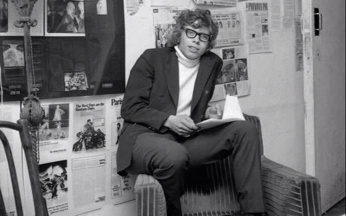 Black and white image.  Richard Branson as a student. He wears thick rimmed glasses and a turtle neck top with a jacket