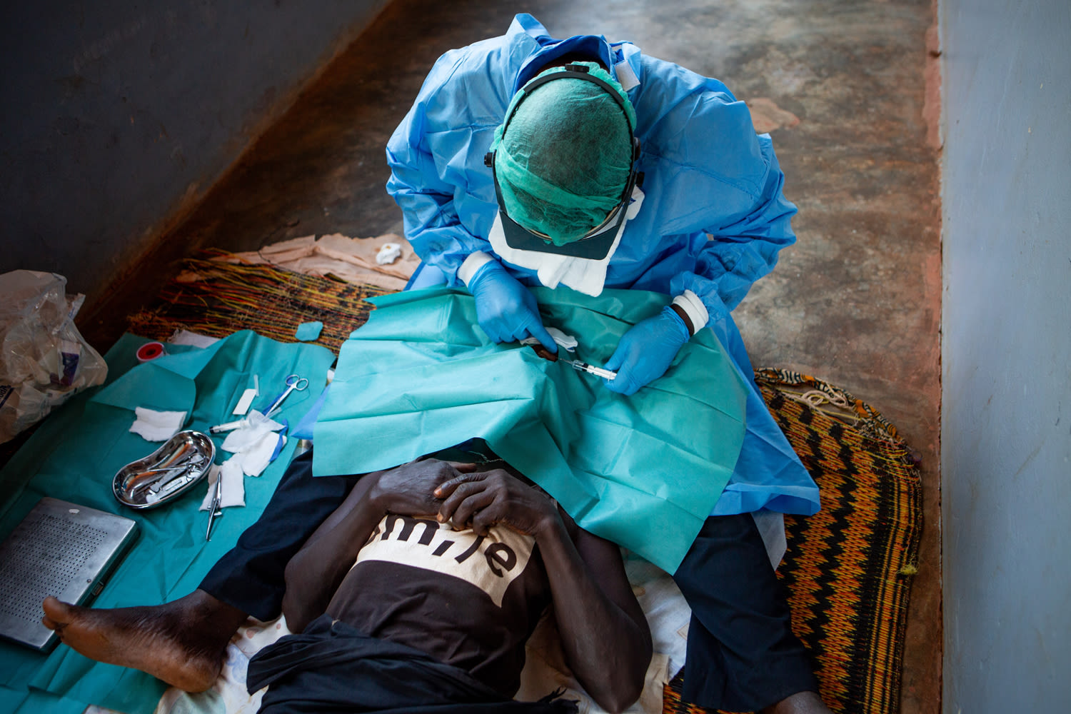 Forma, trachoma surgeon, operates on Nene on the porch of her home in rural Guinea Bissau