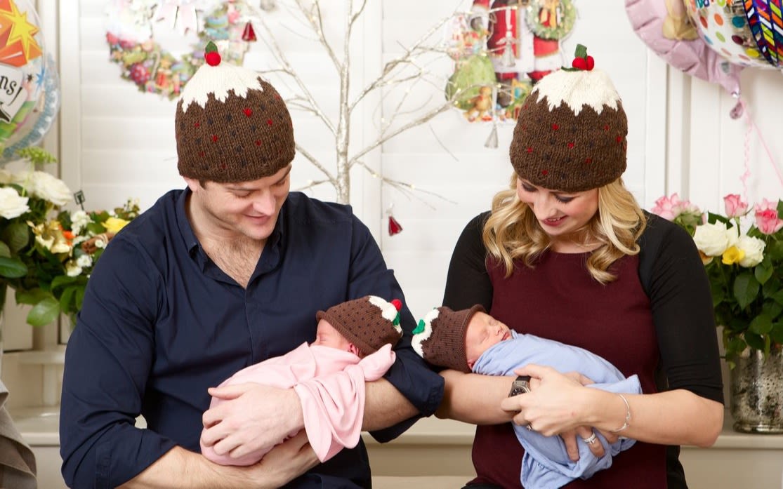 Holly and Freddie wearing christmas pudding hats each holding a newborn baby