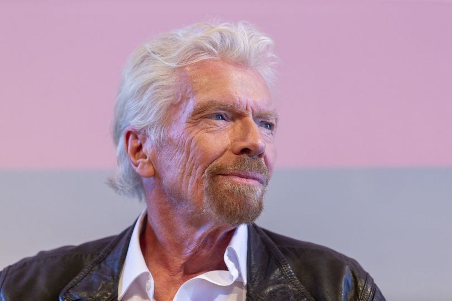 Richard Branson wearing a Virgin Voyages uniform shirt smiling with his thumbs up