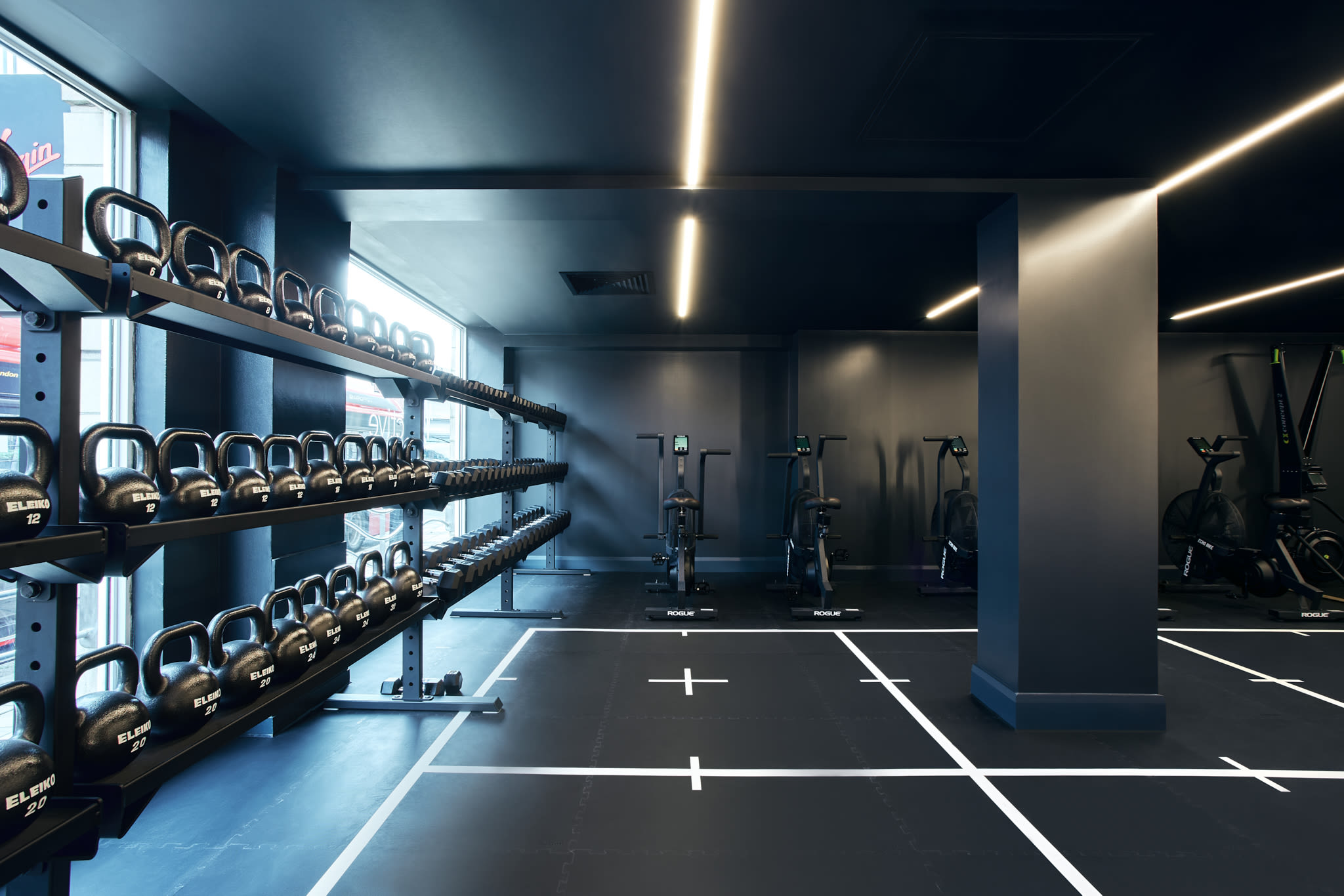 Gym floor with kettle bells on the left hand side and ergonomic bikes in the background
