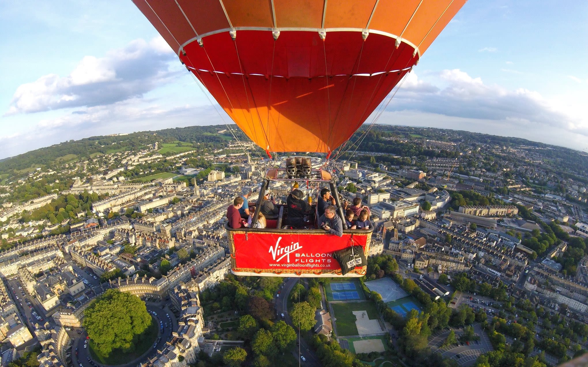 A red Virgin Balloon Flights hot air balloon flies over a city