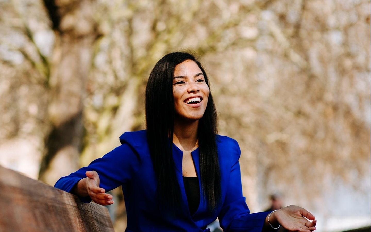 Jacqueline Gomes-Neves sitting on a park bench and smiling