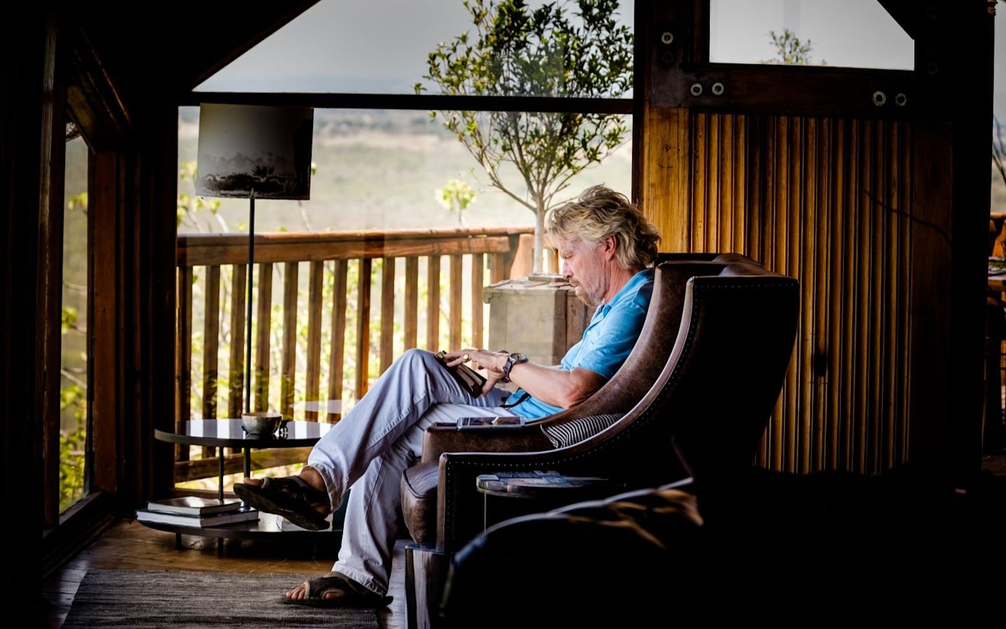 Richard Branson sat in chair crossed legged reading