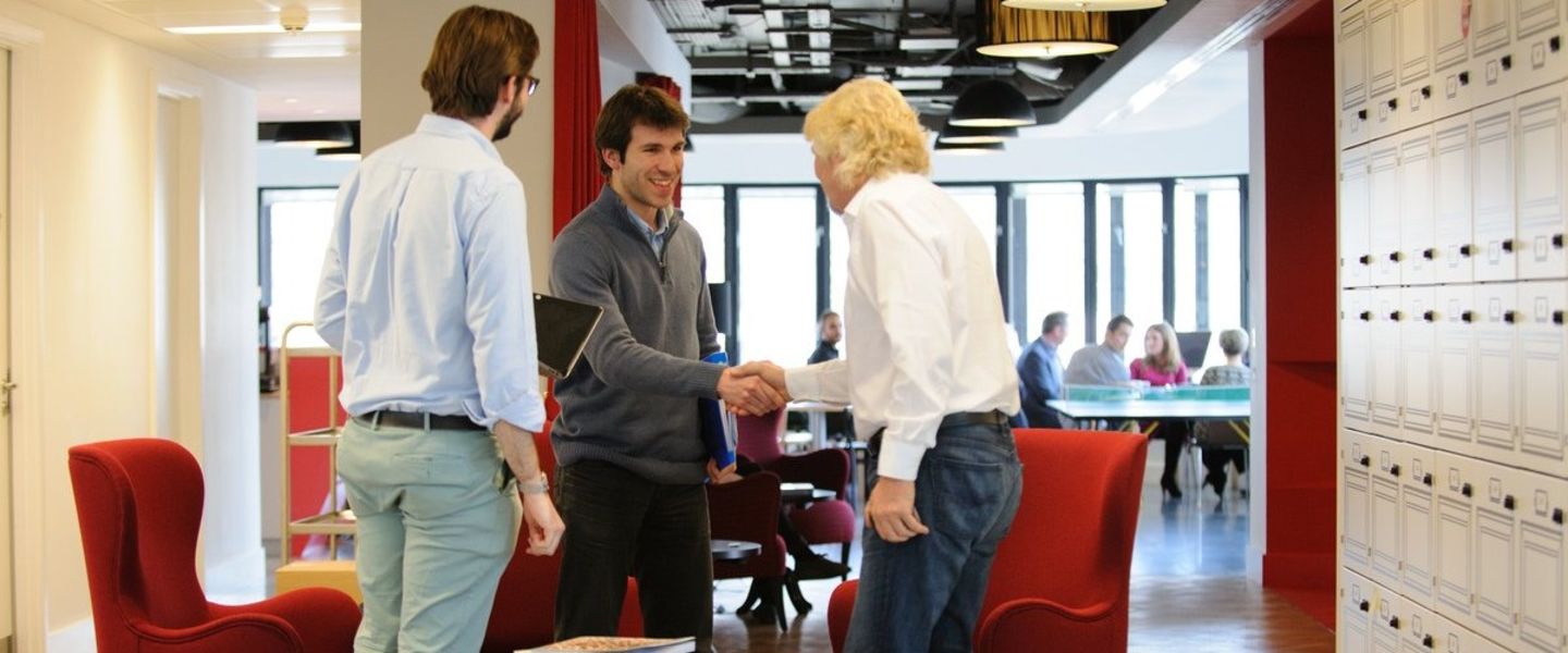 Richard Branson shaking hands with employees at the London office