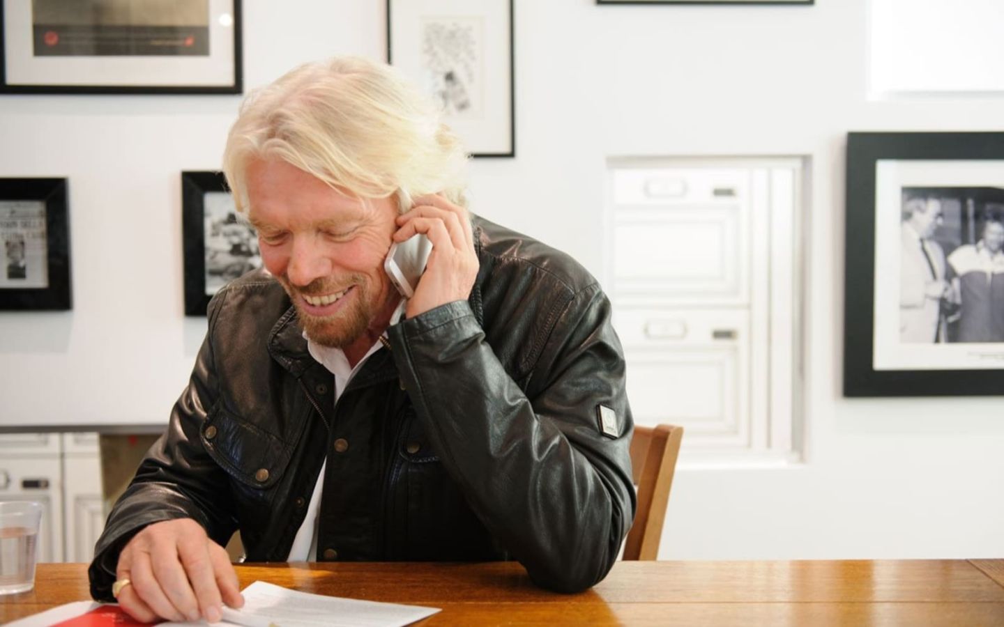 Richard Branson sitting at a table - talking on a mobile phone