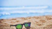 Sunglasses sat in the sand on a beach