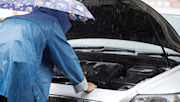 Person checking their engine in the rain.