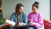 A man and woman sitting together and looking at a SimpliSafe starter kit and smiling