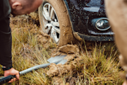 Person using shovel to remove mud from under a tyre