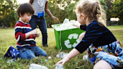 Children putting plastic bottles in a recycling box