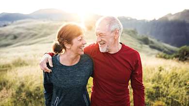 Senior active couple walking on a hill top.